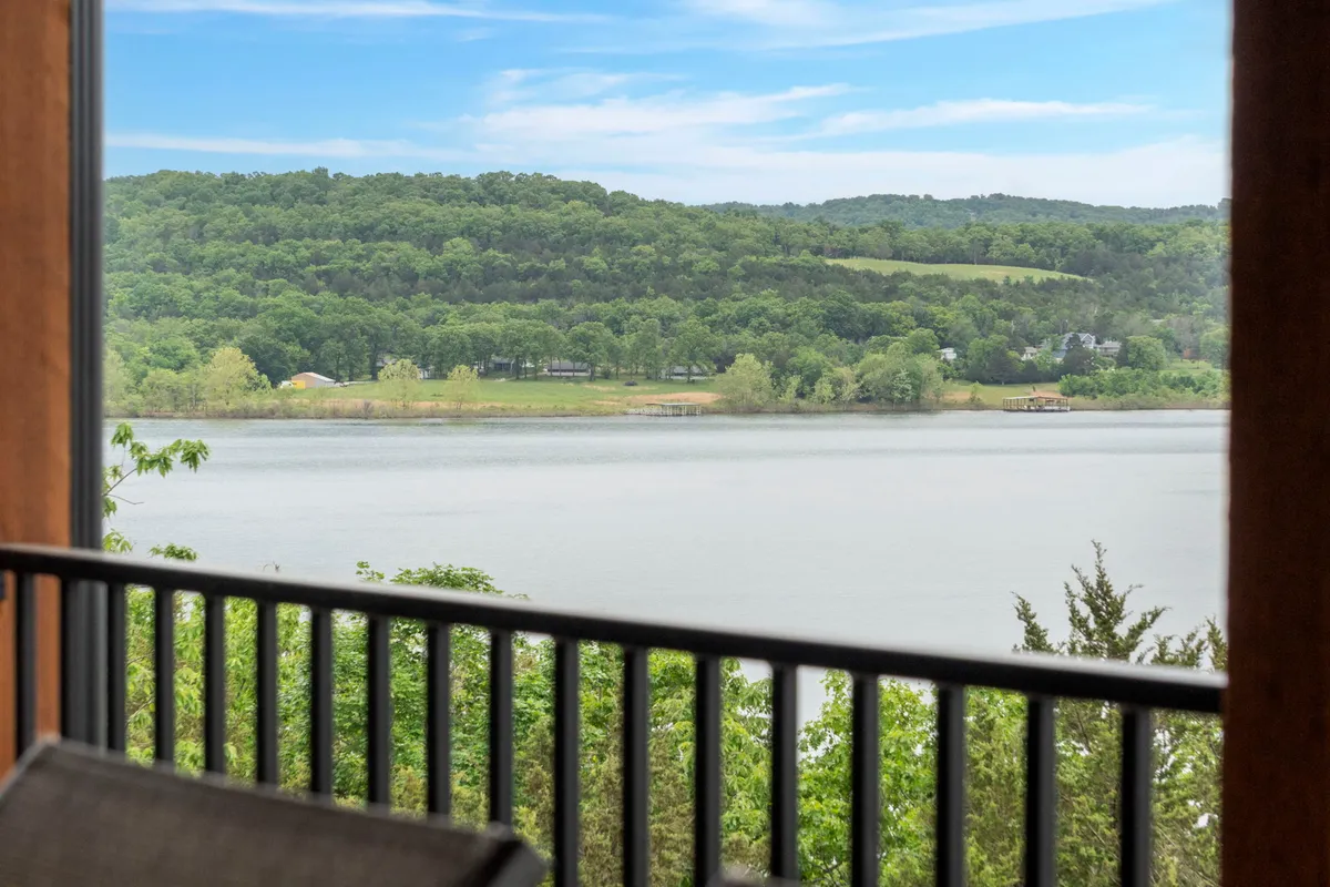 A tranquil lake stretches into the distance, bordered by lush green hills and a wide blue sky. The view is serene, showcasing the natural beauty and outdoor opportunities of the area, such as fishing, boating, and hiking.