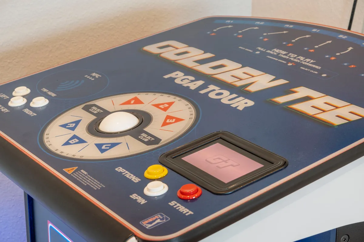 A dedicated arcade zone is highlighted by the presence of a Golden Tee PGA Tour arcade machine, ready for energetic matches and mini-tournaments. The space is designed for fun and interactive entertainment, appealing to both kids and adults.
