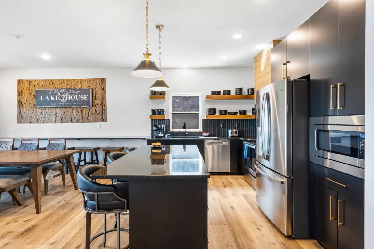 A welcoming kitchen with a large island, adjacent dining table, and artistic wooden wall décor. The space invites both meal preparation and group activities, illustrated by the proximity of the kitchen to the dining area—ideal for cooking classes, themed dinners, or game nights.
