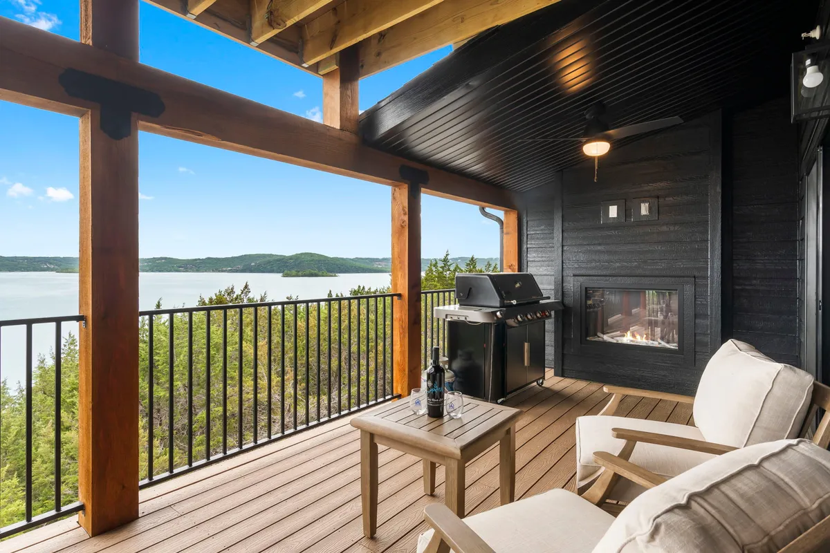 A tranquil outdoor lounge area featuring a built-in grill, cozy seating, and an unobstructed view of the lake. The area is set up for barbecuing and relaxing while enjoying the scenic surroundings.
