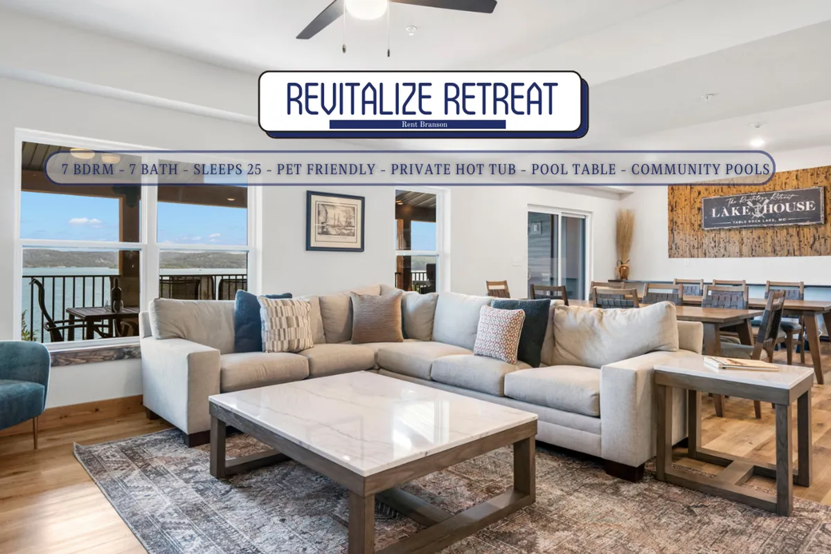 A roomy living and dining area featuring a plush sectional sofa, coffee table, and an adjacent dining area. Large windows provide views of the lake, enhancing the sense of openness and tranquility. The atmosphere is relaxed and inviting, ideal for both lively gatherings and quiet evenings by the fireplace.