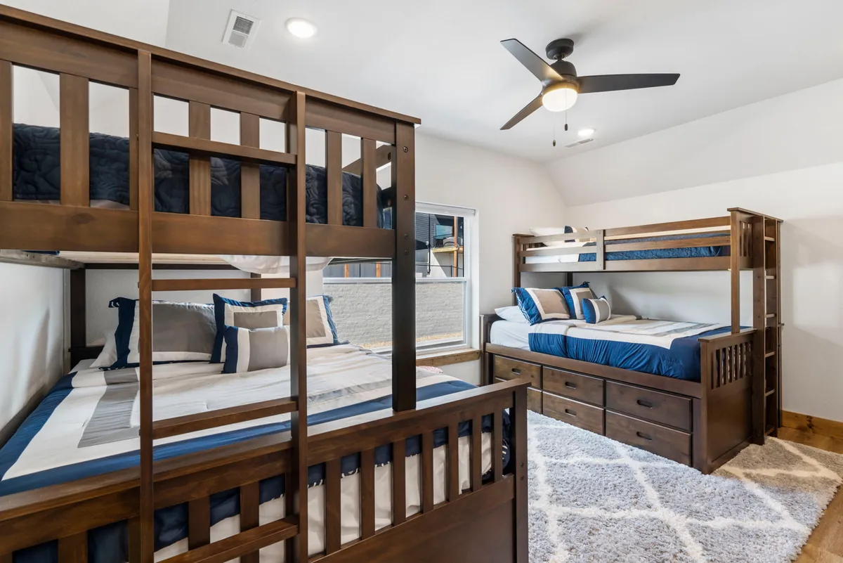 A cozy bunk room with neatly arranged bunk beds, colorful bedding, and built-in storage drawers. The space is playful and family-friendly, ideal for kids, cousins, or friends to share stories and laughter at bedtime.
